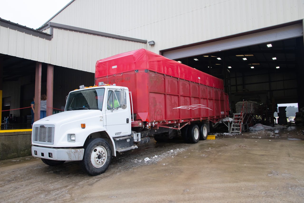 Red trailer truck at a warehouse loading dock, ready for delivery.